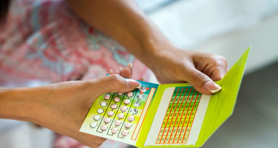 Beautiful young woman holding contraceptive pill or birth control pill